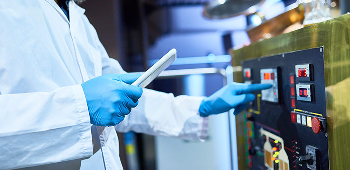 worker pushing buttons on equipment at pharmaceutical manufacturing facilitiy