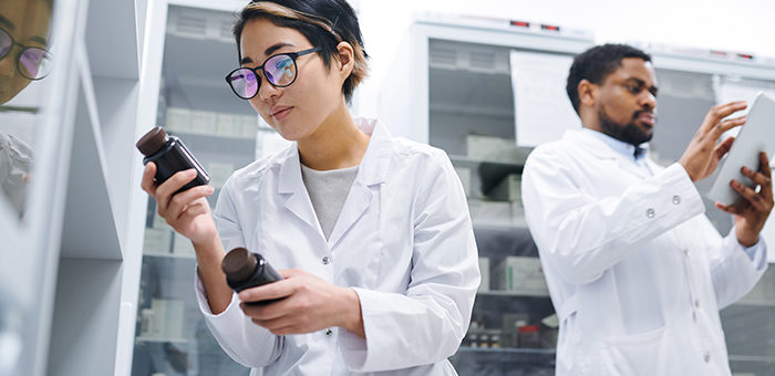 woman and man in lab coats, checking equipment